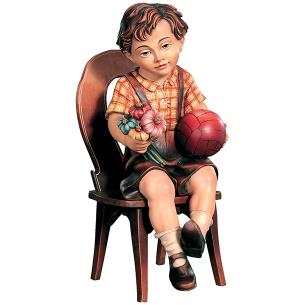 Bub sitzend mit Ball und Blume auf Stuhl